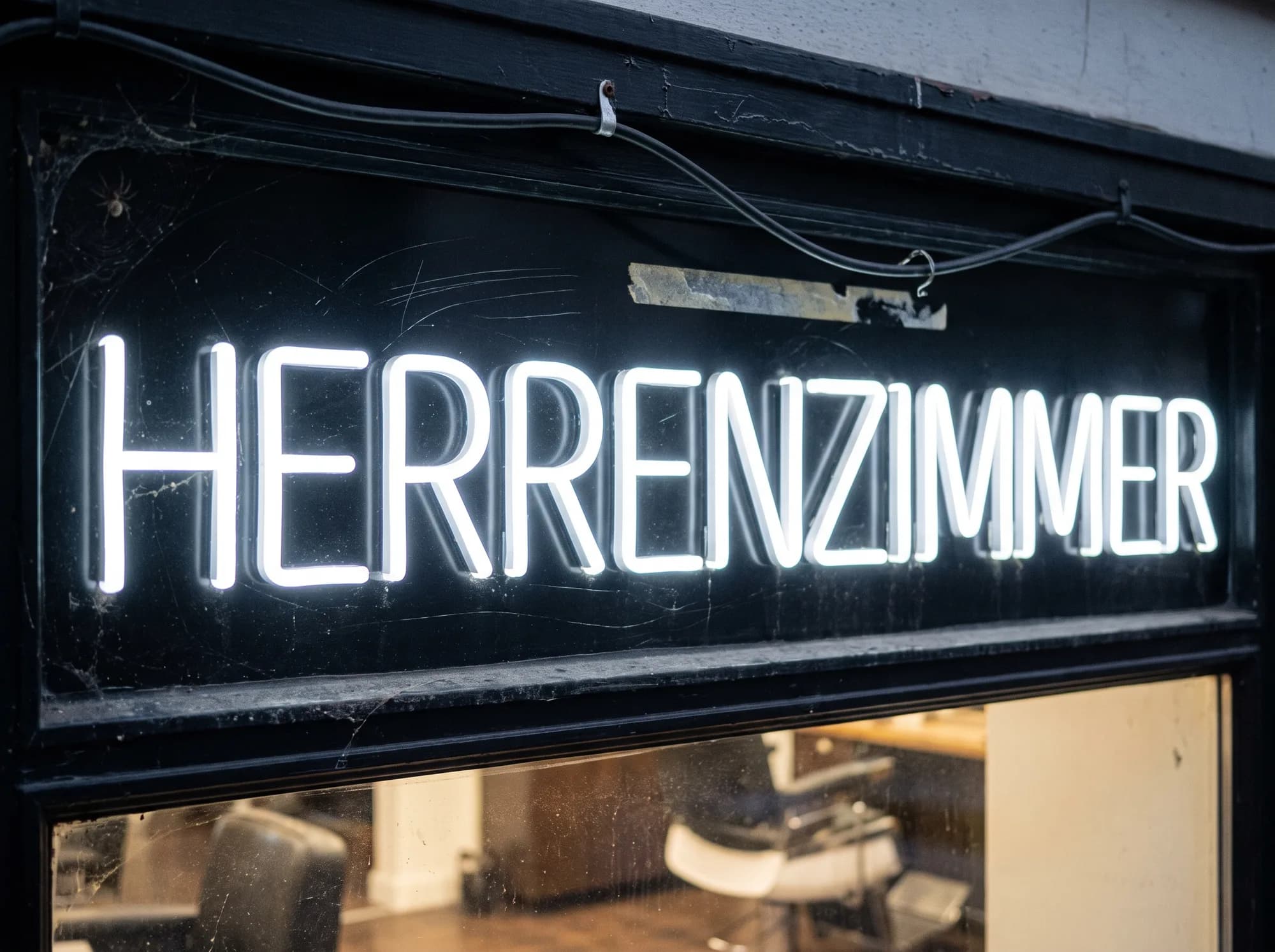 Cool white neon lettering on a black fascia above a barbershop window