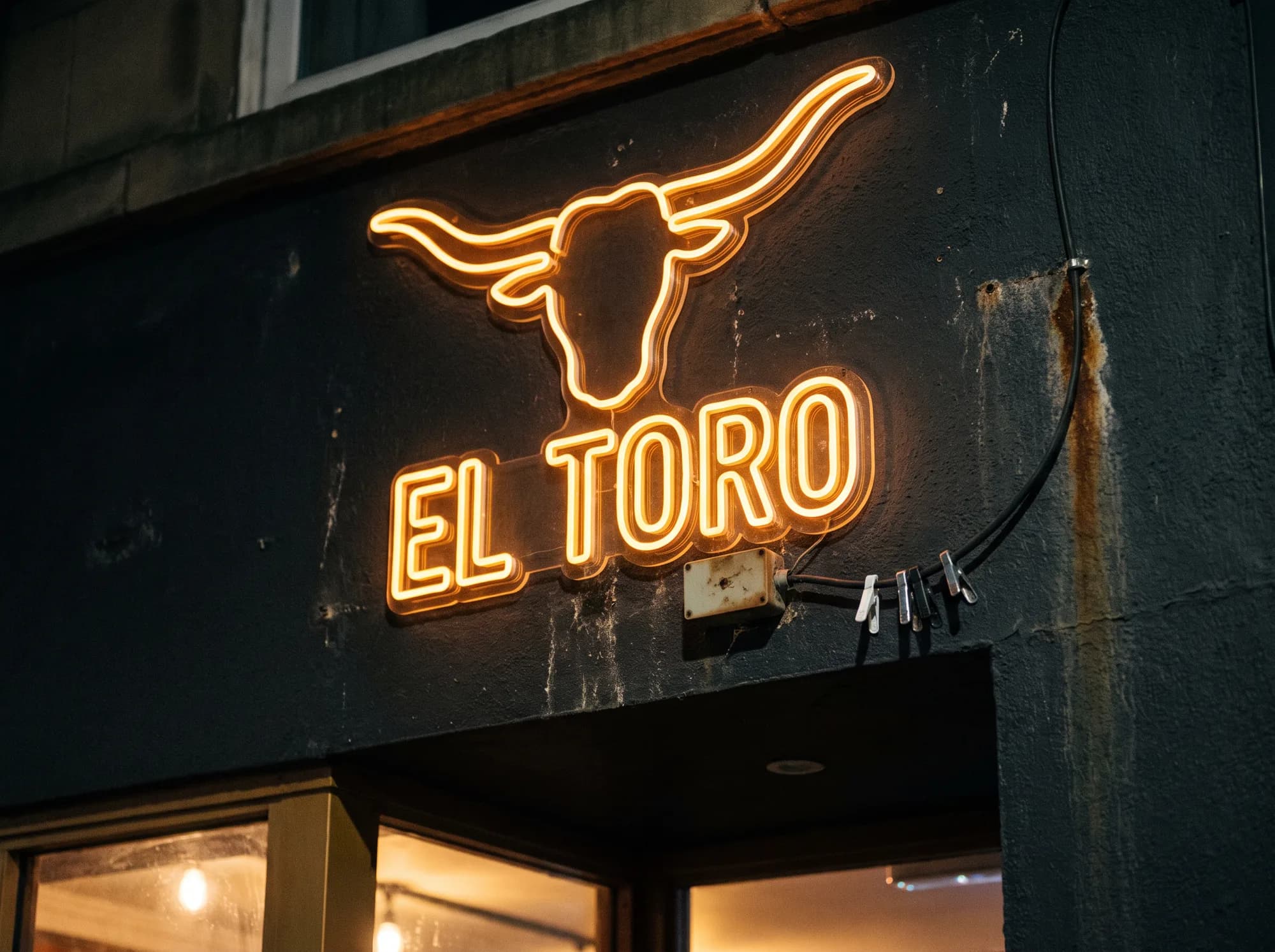 Steakhouse neon sign: a bull's head pictogram above the wordmark, both in outline build