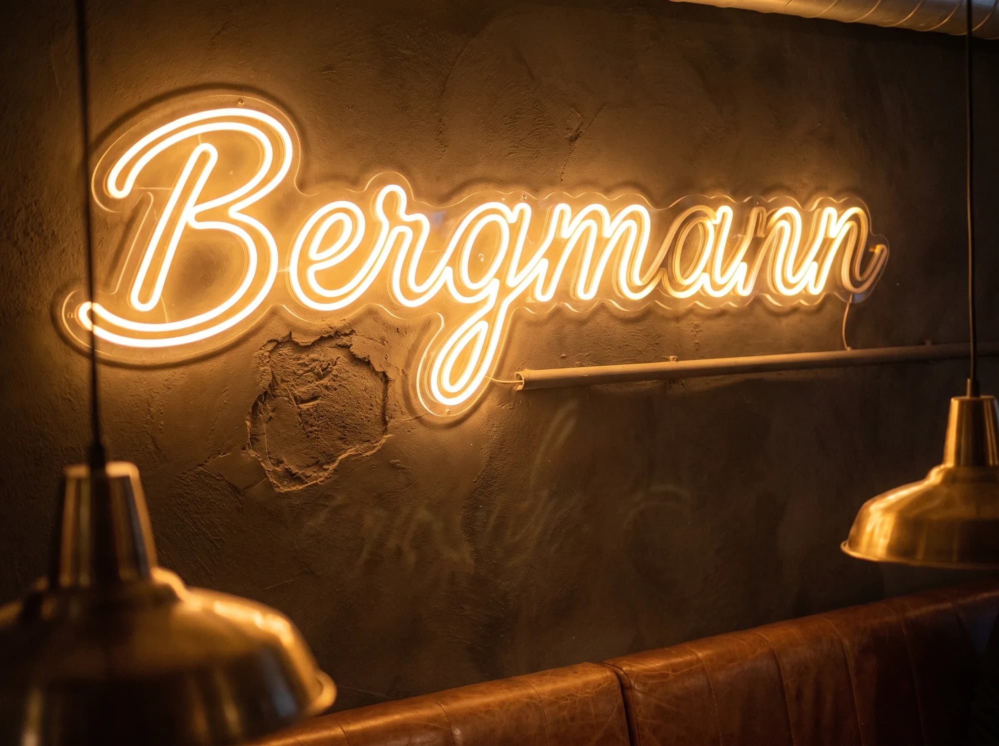 Large-format amber neon script on the back wall of a restaurant